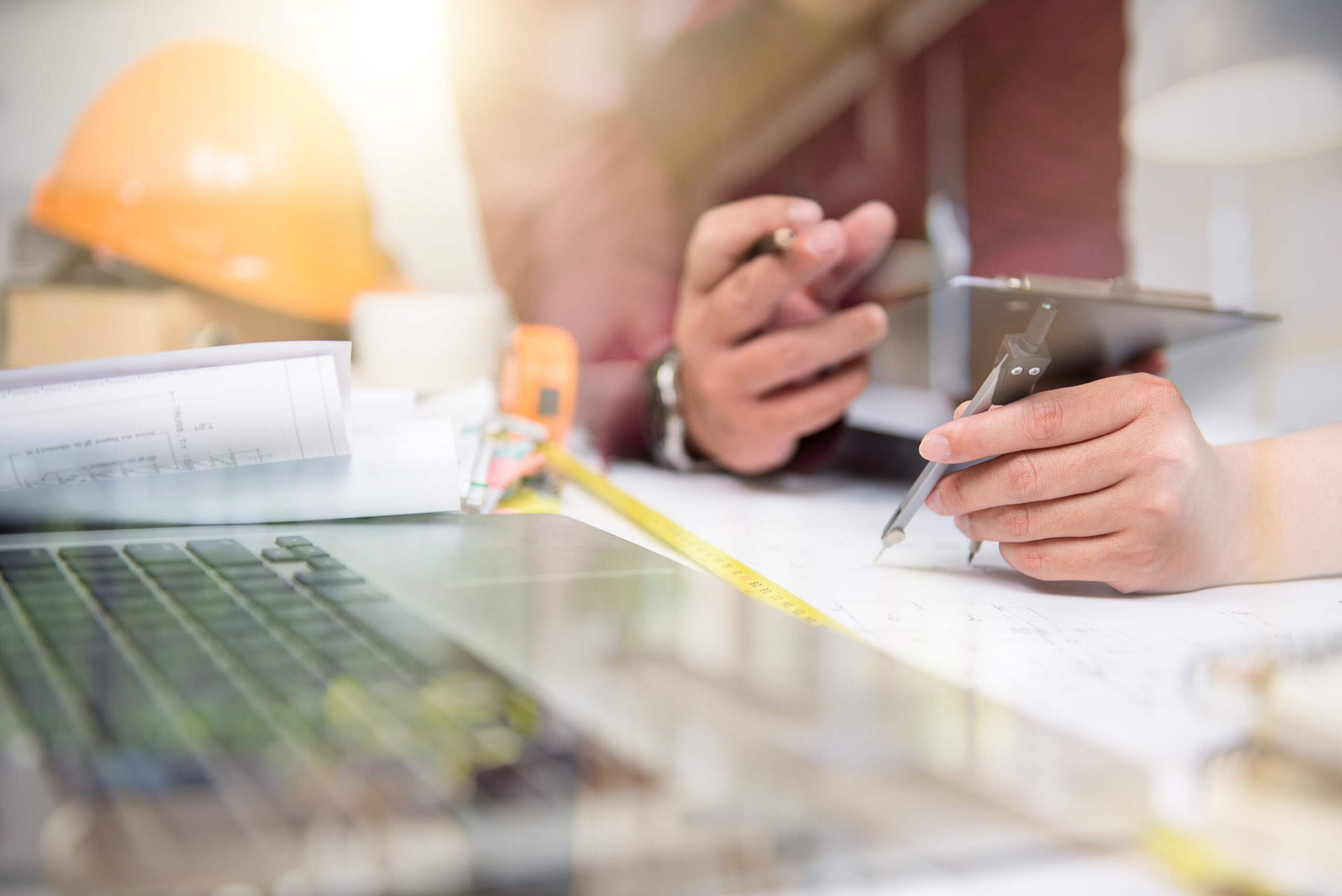 Photo of architectural drawings, hard hat, computer and hands for use by Facilities Space Planners in Santa Clara, CA