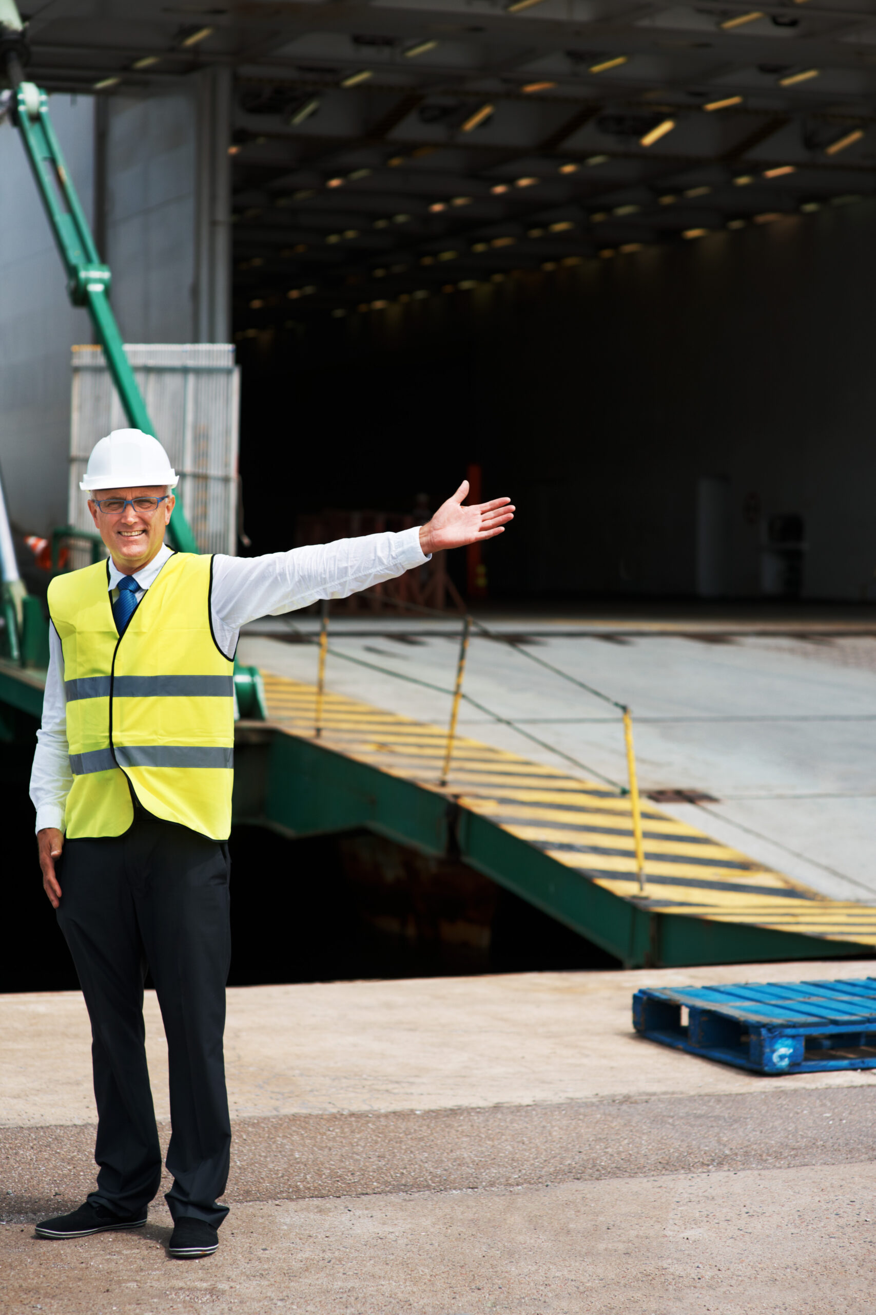 Man smiles with arm out in front of a loading dock in a service yard in Silicon Valley.