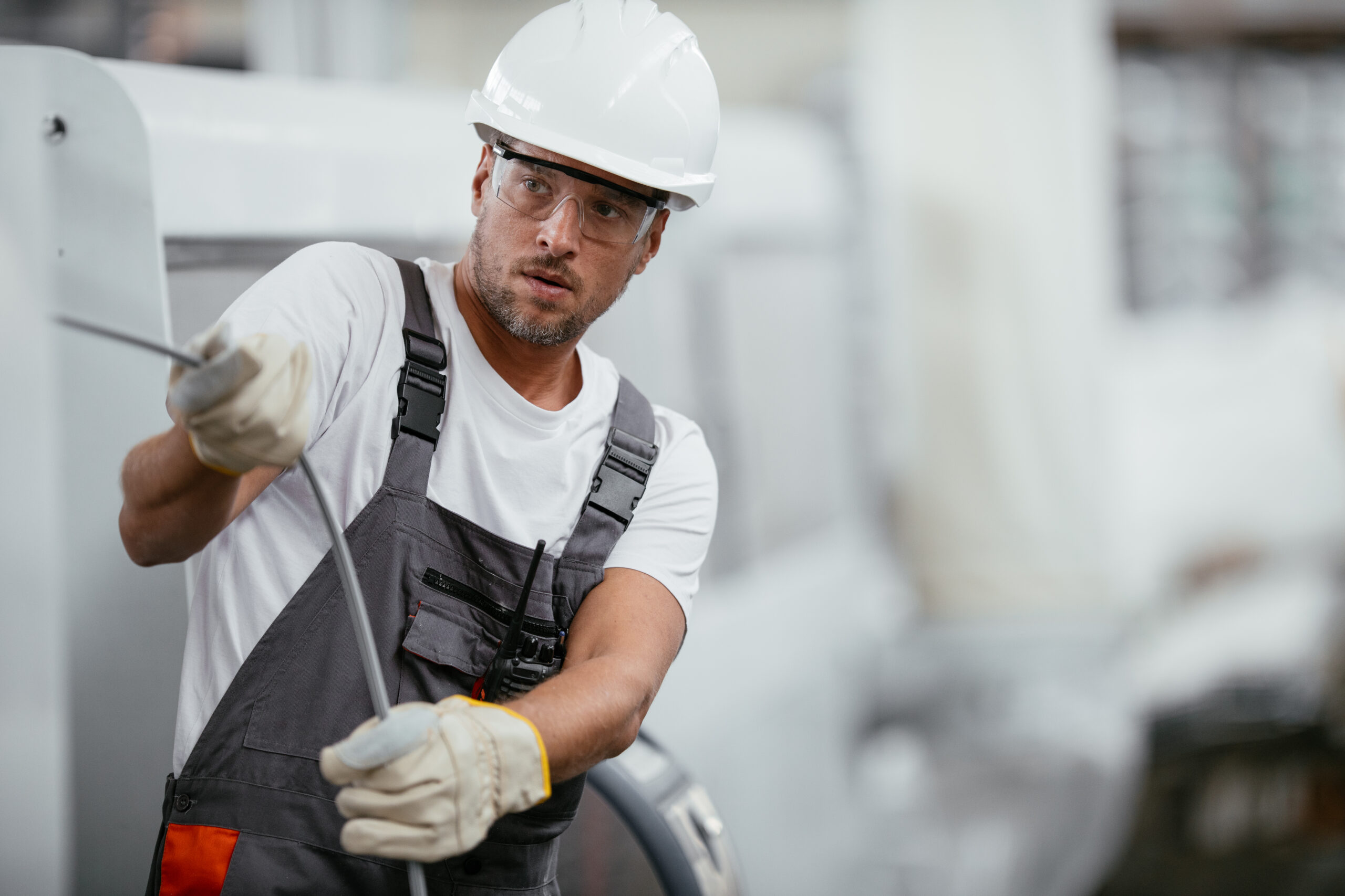 Man in hard hat pulls cable in silicon valley semiconductor research and development facility (R&D).